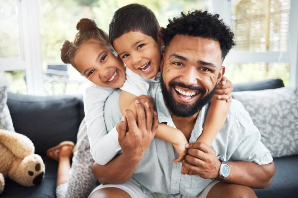 Portrait of a mixed race father,son and daughter bonding together at home. Hispanic boy and girl hugging and holding their father while smiling on the sofa in the lounge