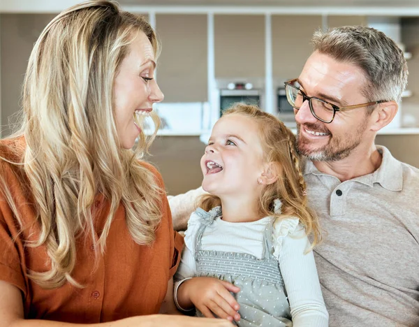 A happy smiling family of three relaxing and spending quality time together in the lounge. Loving caucasian family bonding with their daughter and having a conversation on the sofa at home.