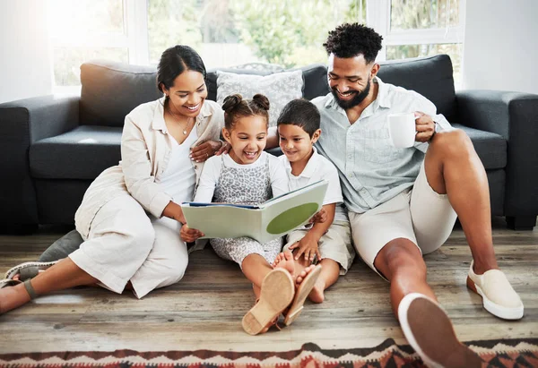 Mixed race family reading a book together on the floor at home. Hispanic mother and father teaching their little son and daughter how to read. Brother and sister learning to read with their parents.