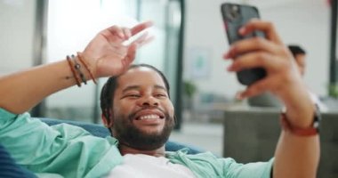 Black man, phone and peace sign on video call with smile for social, networking or communication at the office. African American man relaxing on break talking on smartphone videocall at the workplace.