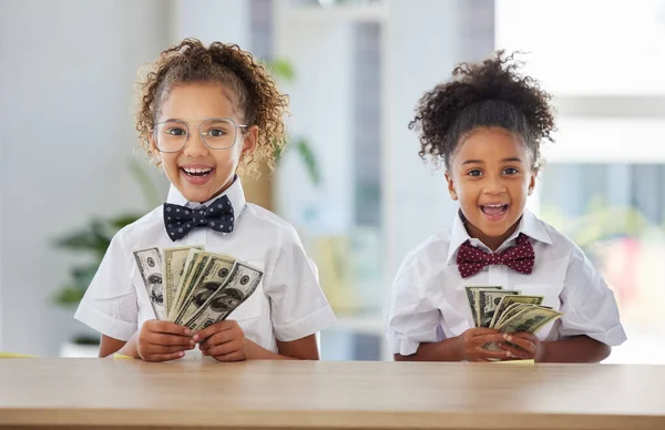 Were the best money makers in the company. two adorable little girls dressed as businesspeople sitting in an office and holding money