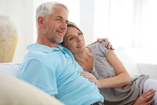 Old couple, hug and thinking about future in retirement at home or love, care and support. Commitment of man and woman in healthy marriage with trust, life insurance and security on living room couch.