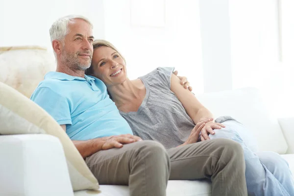Senior couple, retirement and thinking on a couch at home with love, care and support from life insurance. Commitment of a man and woman in a healthy marriage with security on living room couch.