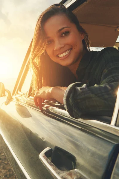 Portrait, driver and road trip with a black woman in a car at sunset during summer vacation or travel. Nature, window and drive with an attractive young female sitting in transport for adventure.