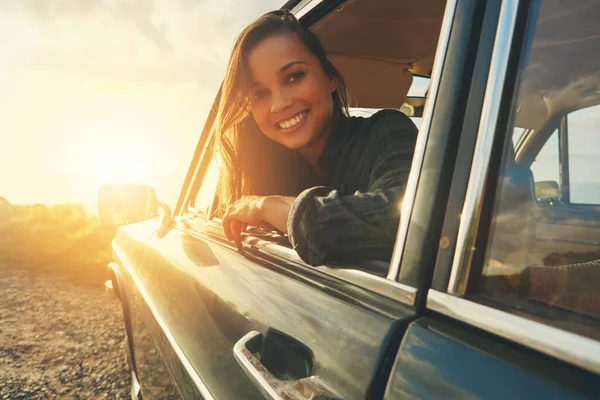 Portrait, travel and road trip with a black woman in a car at sunset during summer vacation or holiday. Nature, window and drive with an attractive young female sitting in transport for adventure.