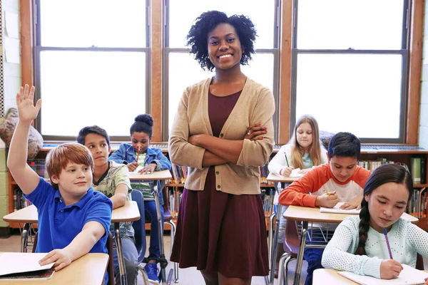 Learning portrait, black woman and student with question in classroom or school. Education, arms crossed and scholarship boy raising hand to answer questions, studying or help with happy teacher