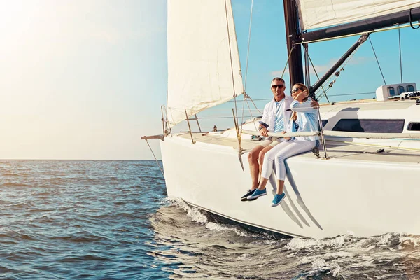 Yacht, travel or love and a mature couple sitting on a boat out at sea with blue sky mockup and flare. Ocean, summer and luxury with a man and woman on a ship to relax on the water in nature.