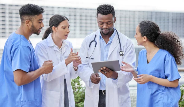 Solving problems as a team. a group of doctors using a digital tablet against a city background