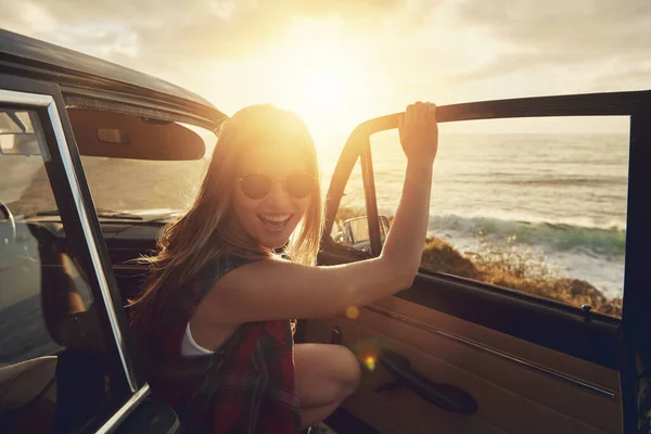 Woman, sunset portrait and road trip by car door with smile, beach and happiness for summer vacation. Happy gen z girl, suv and sunshine with sunglasses, outdoor adventure and holiday by ocean waves.