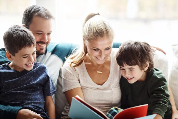 Mom, dad and kids reading books on sofa for storytelling time with smile in happy family home. Love, learning and couple with children, book and fantasy story on couch, growth and child development