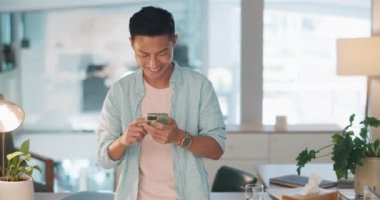 Cellphone, networking and Asian man on social media in the office typing on a lunch break. Technology, happy and male employee with a smile browsing internet or mobile app with cellphone in workplace.