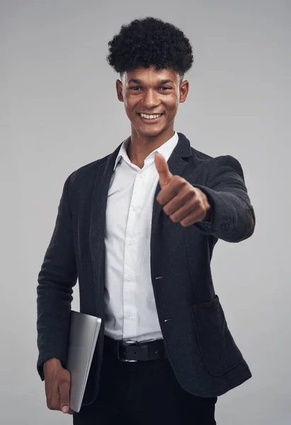 You can do this, just keep at it. Studio shot of a young businessman showing thumbs up against a grey background