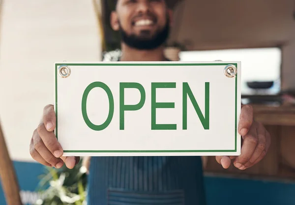 Open and ready to serve. a businessman holding an open business sign