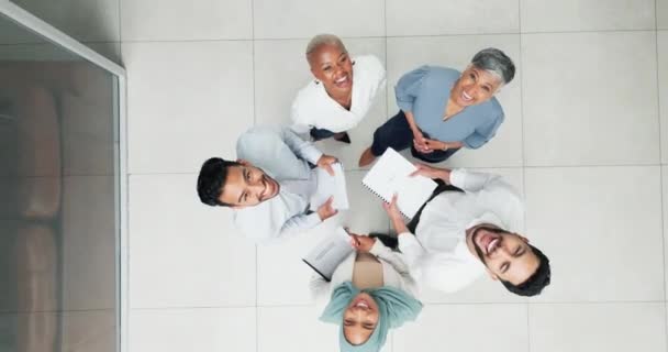 在一个办公室里一起工作的时候 和一个商业团队一起协作 一起在头顶上拥抱 一起欢笑 从上面站在一个圆圈里的男女员工的脸 团队合作和文件记录 — 图库视频影像