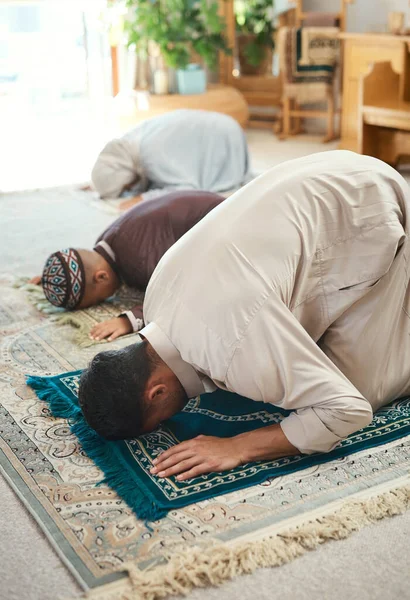 stock image Prayer is as important as breathing. a young muslim couple and their son praying in the lounge at home