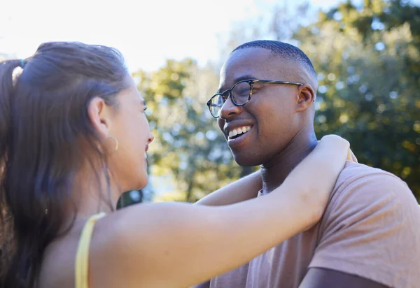 Interracial couple, smile and hug for love, care or embracing relationship together in a nature park. Happy black man hugging woman and smiling in happiness for romance, embrace or support outside.