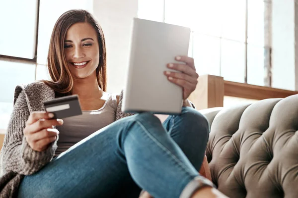 Payment, digital tablet and credit card by woman on a sofa, ecommerce and online shopping in her home. Girl, online shopping and relax checking debit card for purchase or subscription in living room.