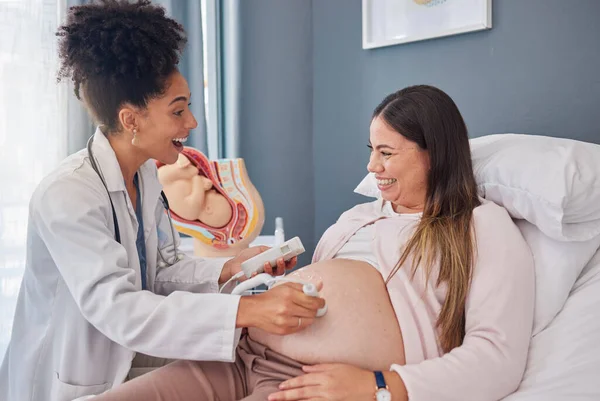 Ultrasound doctor, woman excited and hospital bed with happiness, support and family planning for future. Black woman medic, pregnant woman and medical tech consulting on stomach for wellness of baby.