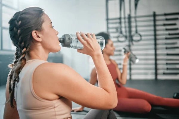 Fitness, gym and relax friends drinking water for sports thirst hydration, performance workout or exercise running. Athlete health, fatigue and tired women with liquid bottle drink after training.