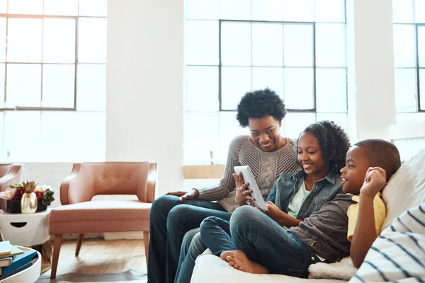 Family with tablet, watch and relax at family home together, spending quality time together with technology. Black people, mother and children on sofa with device, internet wifi and social media.