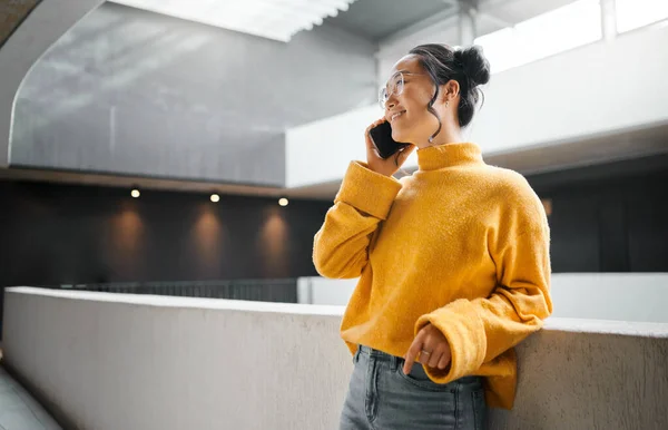 Phone call, communication and mockup with an asian woman talking while standing in a hallway. Mobile, networking and conversation with an attractive young female speaking on her smartphone indoor.