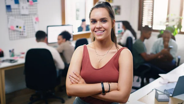 Dont strive to be better, strive to be the best. Portrait of a confident young businesswoman working in a modern office with her team in the background