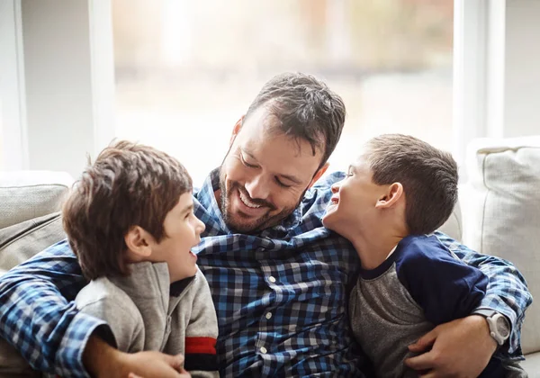 Family home, boys and dad with hug on sofa for conversation, love or bonding for childhood development. Happy people, relax or joke together in living room for fun, happiness or quality time in house.