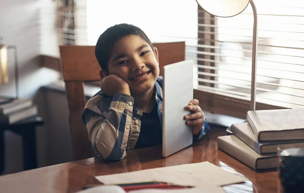 Enhancing the learning process with the right tools. an adorable little boy using a digital tablet while completing a school assignment at home