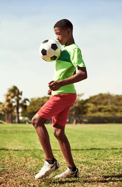 Good players practice until they get it right. a young boy playing soccer on a sports field