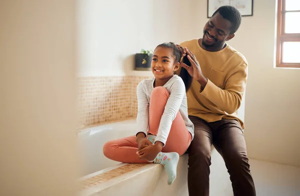 Excited child, father and brushing hair in family home bathroom with love and support. Black man teaching kid self care, health tips and wellness with communication, talking about trust and beauty.