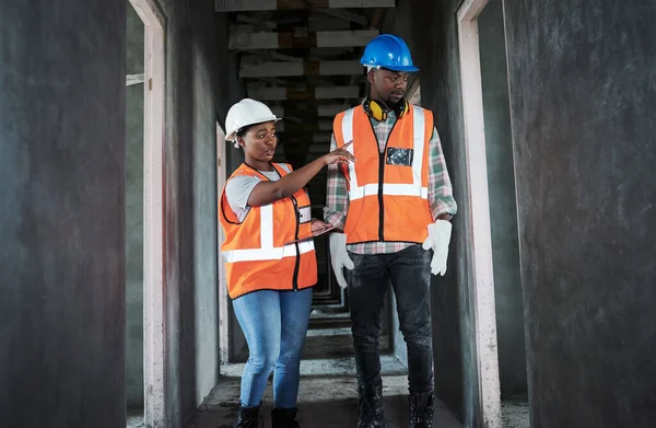 Growing a community from the ground up. a young man and woman using a digital tablet while working at a construction site