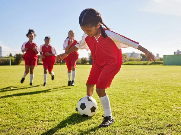 Soccer, training or sports and a girl team playing with a ball together on a field for practice. Fitness, football and grass with kids running or dribblinf on a pitch for competition or exercise.