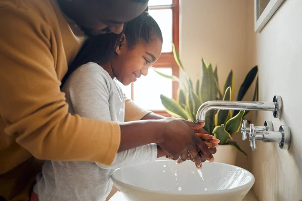 Black family, father and child washing hands with clean water in home bathroom. Man teaching girl while cleaning body part for safety, healthcare and bacteria for learning about health and wellness.