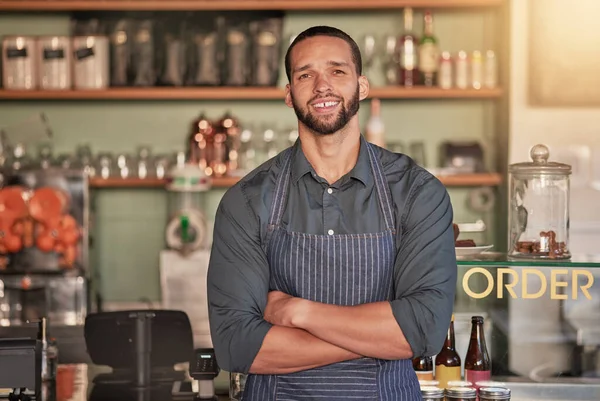Portrait, cafe and barista man with arms crossed ready to take your order. Coffee shop, waiter and confident, happy and proud young male employee from Brazil or small business owner of cafeteria