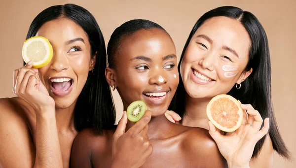Face, fruits and women in portrait with cream for facial care, beauty and natural cosmetics isolated on studio background. Sunscreen, vegan and different skin with skincare, moisturizer and playful.