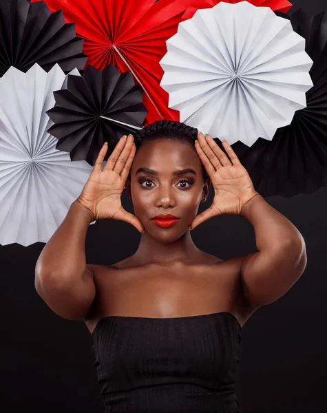 Ive never seen a style that I dont like. Studio shot of a beautiful young woman posing with a origami fans against a black background