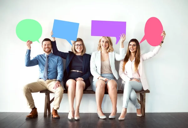 What could be possibly on your mind. a group of work colleagues seated next to each other while holding speech bubbles against a white background