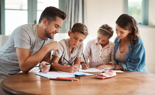 Homework can be a fun way to connect with family. a happy young family of four doing homework together