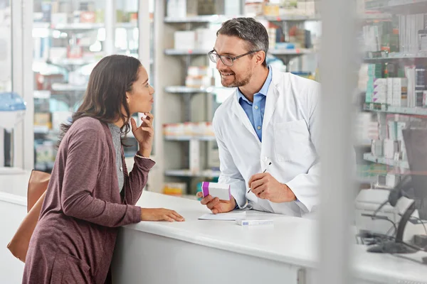 Pharmacist, customer and health with medicine and advice, discussion and service in pharmacy, advice and pills prescription. Healthcare, medical store with pharmaceutical drugs, man and woman talk.
