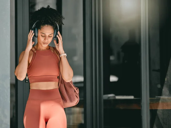 Fitness, walking and black woman listen to music, relax podcast or radio for calm, stress relief or wellness mockup. Headphones, leaving gym and mock up girl on travel after training workout exercise.