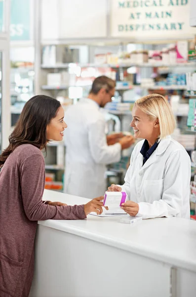 Wellness, health and happy pharmacy customer at store counter for medicine expertise with smile. Pharmaceutical advice and opinion of woman pharmacist helping girl with medication information