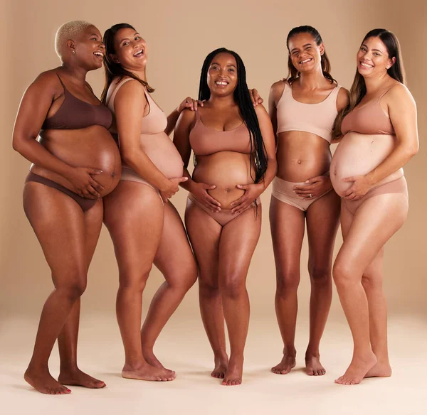 Pregnancy, community and portrait of friends in studio for diversity, motherhood and prenatal wellness. Maternity, love and pregnant women showing their baby bump stomach together by beige background.