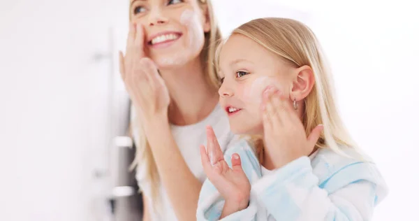 Skincare, mother and daughter home spa day washing their face in bathroom or apply beauty product, lotion or face mask while bonding at home. Happy woman and girl child doing morning skin routine.