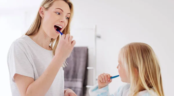 Toothbrush, mother and girl cleaning their teeth in the morning in the bathroom of their family home. Happy, bond and mom doing a dental hygiene routine for health with oral products with her child