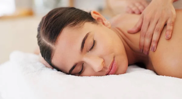 Health, relax and woman getting back massage at luxury spa lying on table with smile and massage therapist hands on back. Wellness, body care and physiotherapy service at beauty salon for happy women.