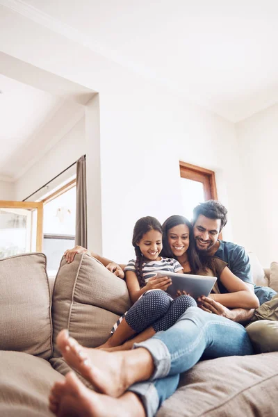 Family entertainment sorted with smart technology. a mother and father using a digital tablet with their daughter on the sofa at home