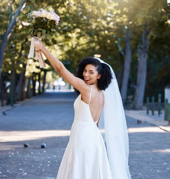 Bride, wedding and black woman with flowers at park outdoors. Portrait, marriage or beauty of happy female holding up floral bouquet of roses to celebrate at party, ceremony event or love celebration.