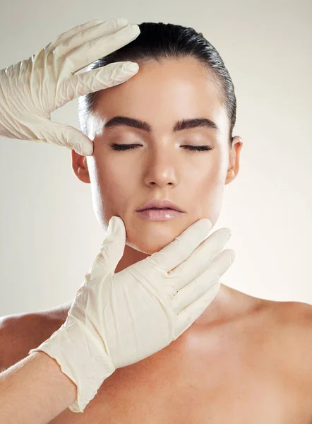 Patient, beauty and plastic surgery with hands on woman face for dermatology collagen cosmetics. Headshot of skincare model person with cosmetologist gloves for cosmetic filler for facial skin lines.