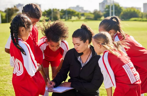 Planning, sports or coach with children for soccer strategy, training or health goals in Canada. team building, teamwork and woman coaching group of girls on football field for game, match or workout.