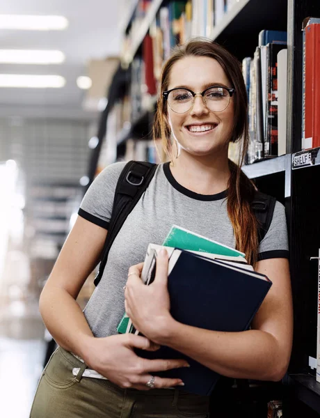 Who wants to be my study buddy. Portrait of a happy young woman carrying books in a library at college